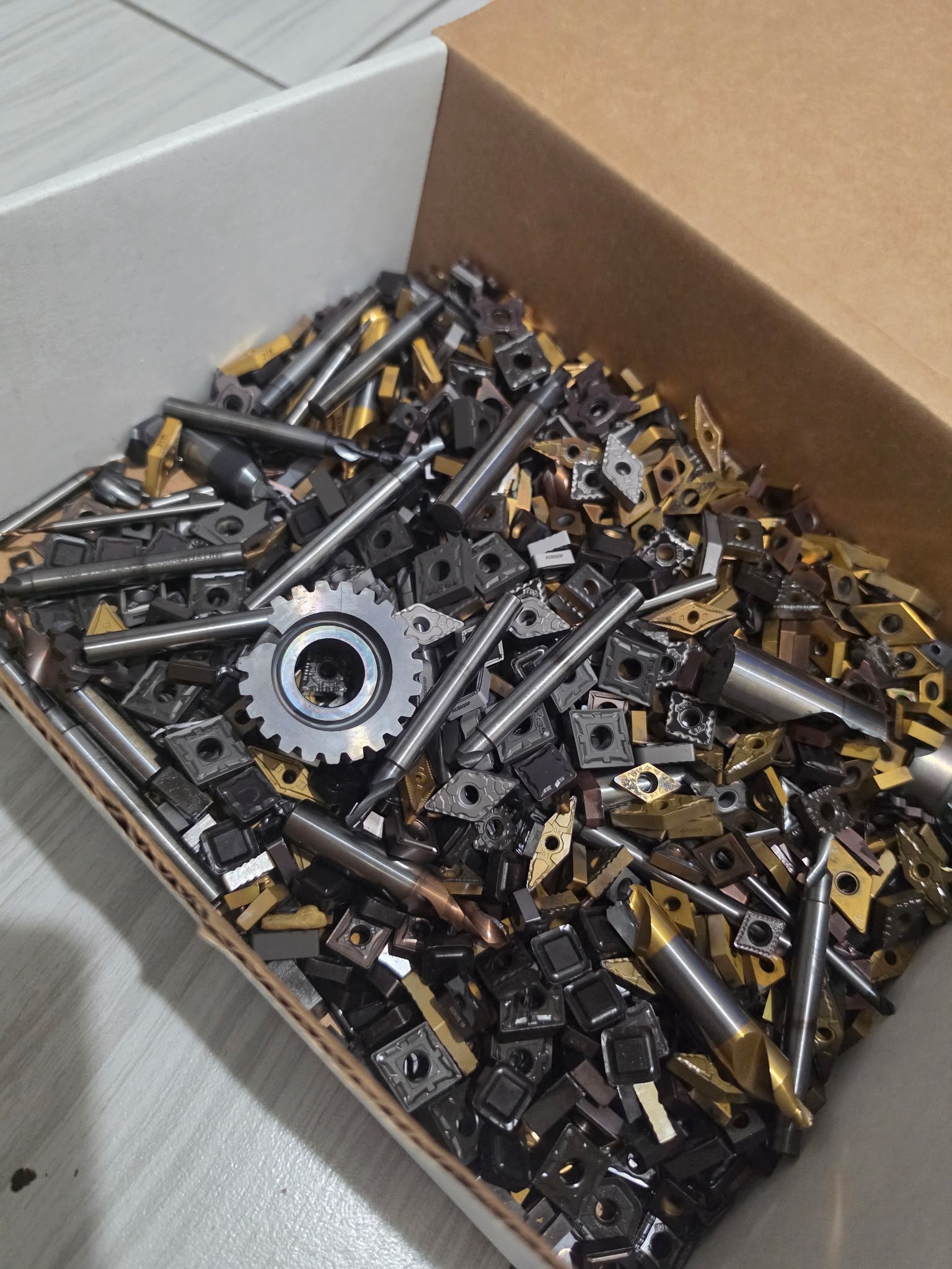 Mixed carbide inserts and cutters in a box for buyer review.