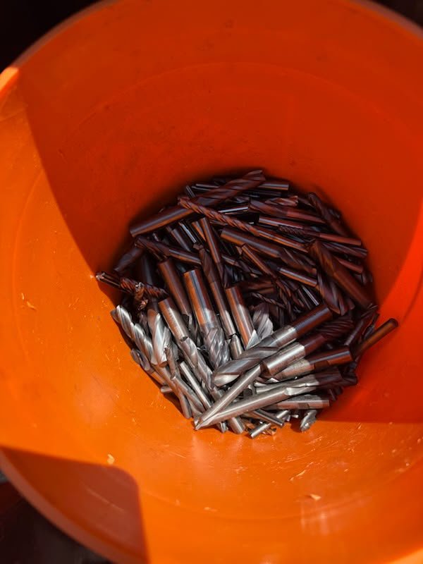 Solid carbide end mills grouped in an orange shop bucket.