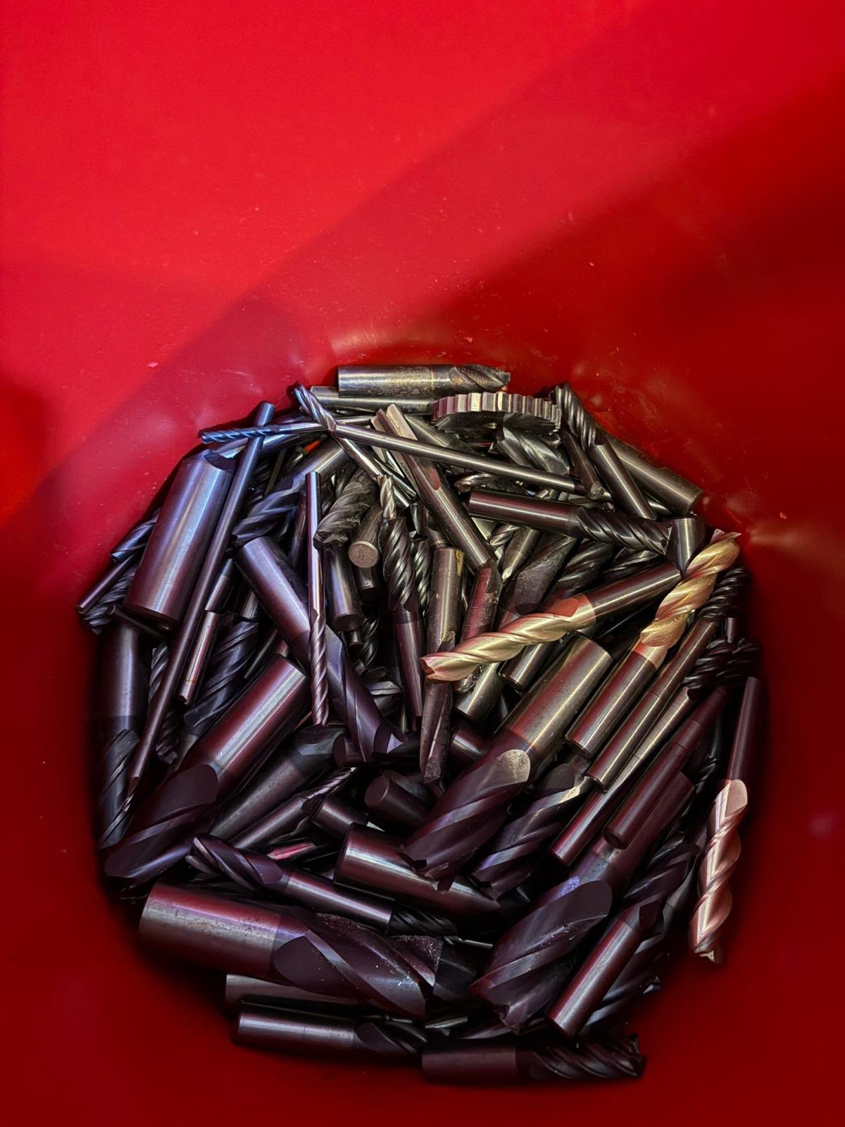 Solid carbide end mills collected in a red bin.